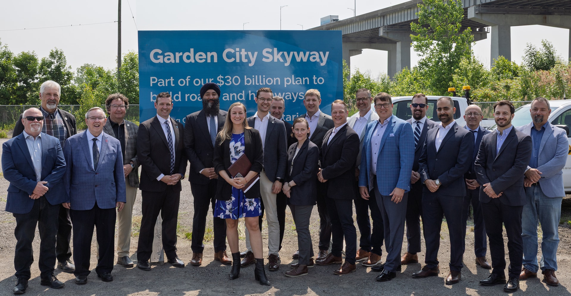A group of people poses for a photo in front of the Garden City subway sign.