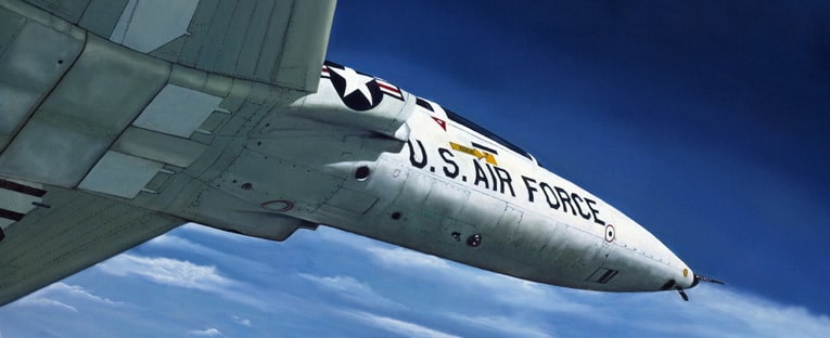 A close-up view of a U.S. Air Force jet soaring through a clear blue sky.
