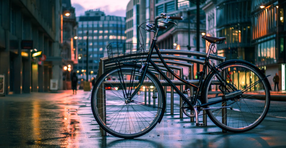 A bicycle is parked on a quiet street as dusk settles, casting soft shadows on the pavement.
