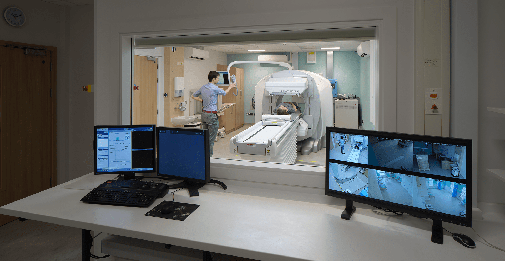 A hospital room featuring two monitors and a man sitting beside them, focused on the screens.