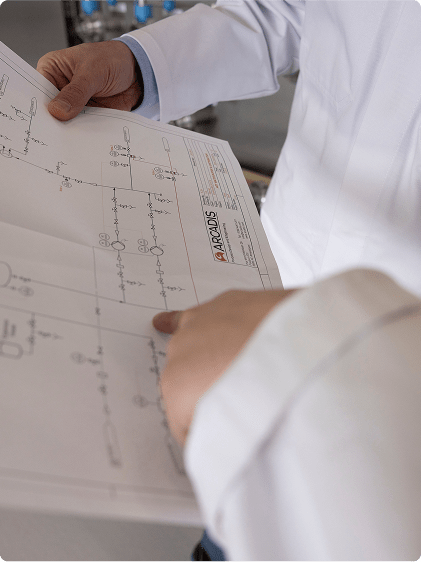 A man in a lab coat is holding a blueprint, indicating his involvement in research or design work.