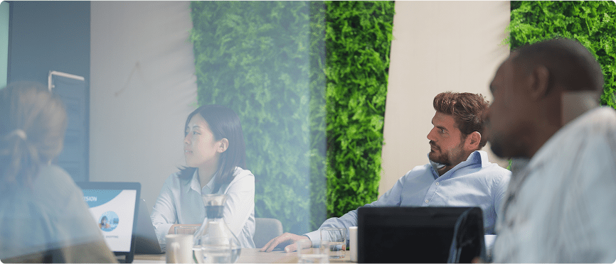 A group of people gathered around a table, focused on a computer screen in front of them.