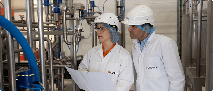 Two lab-coated professionals studying an object intently in a scientific workspace.
