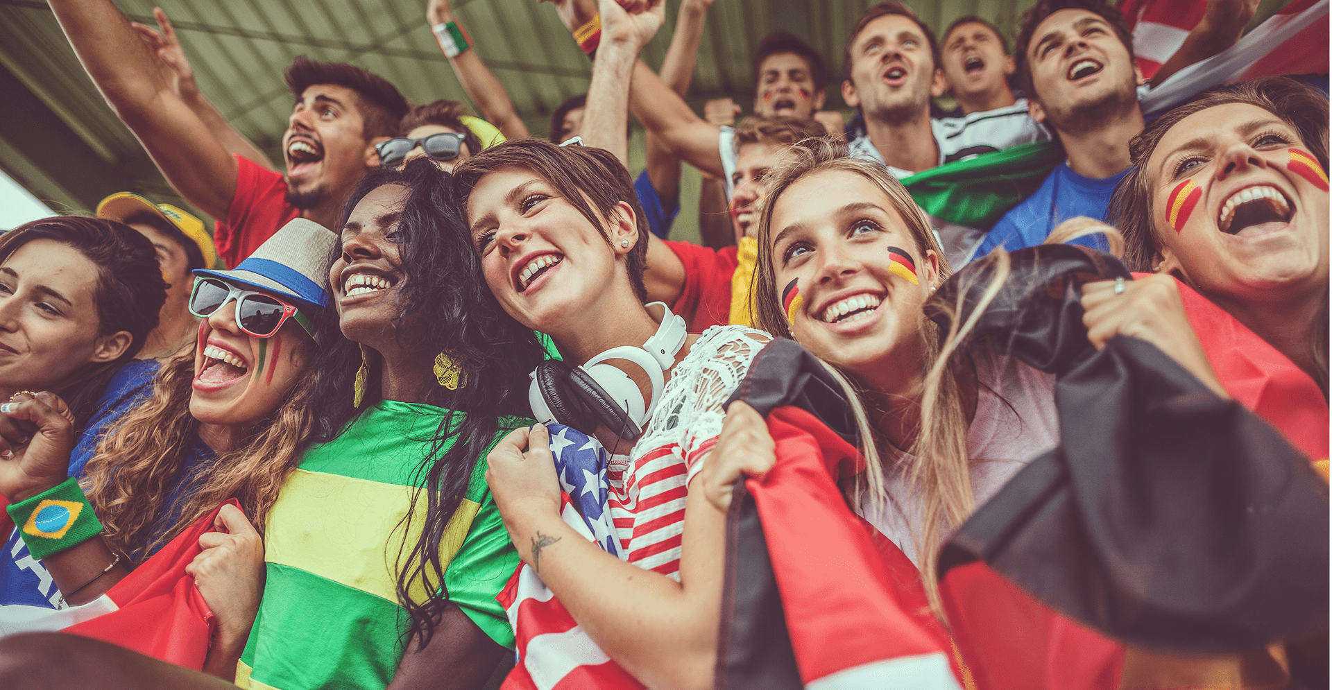 A diverse group of individuals joyfully holding flags, showcasing unity and celebration with bright smiles on their faces.