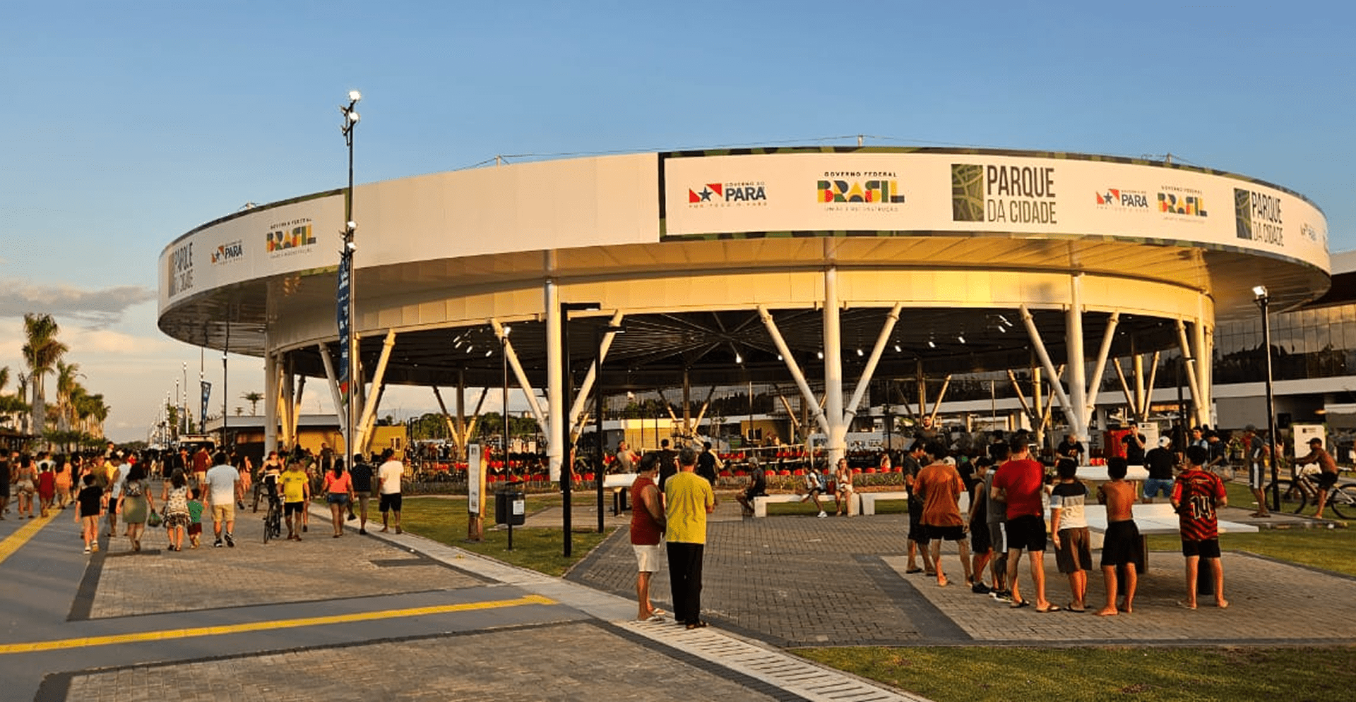 Several individuals gather around a spacious outdoor arena, engaged in conversation and watching the activities.