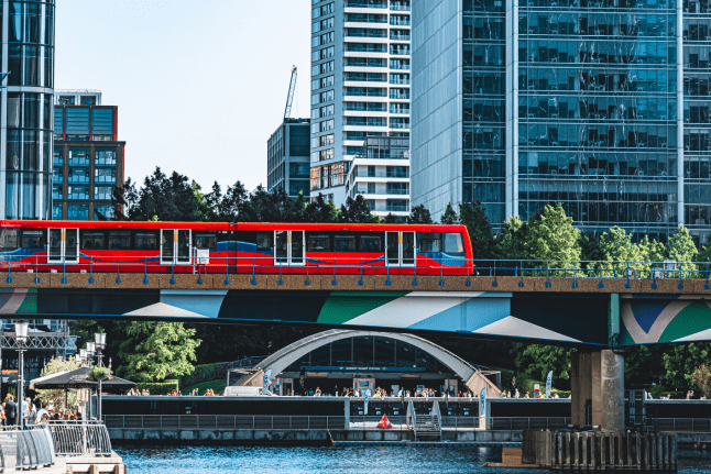 A red train crosses a bridge, showcasing its vibrant color against the landscape.