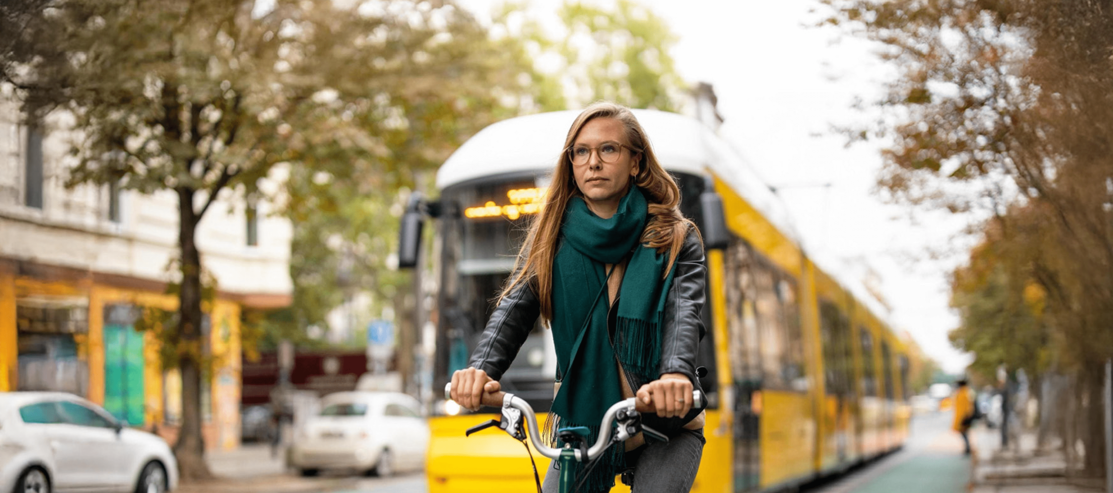 A woman on a bicycle navigating through a vibrant city street, with shops and pedestrians in the background.