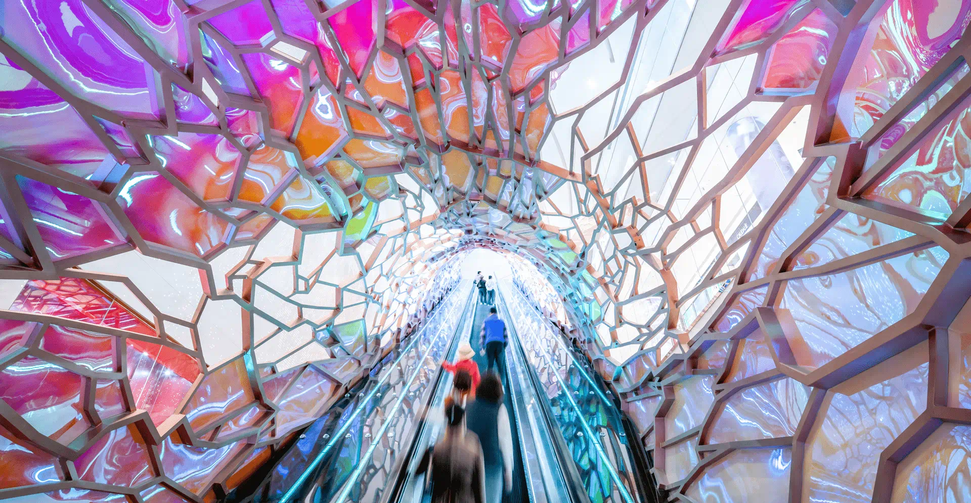 A vibrant tunnel filled with colors, featuring people walking through, creating a lively and dynamic atmosphere.