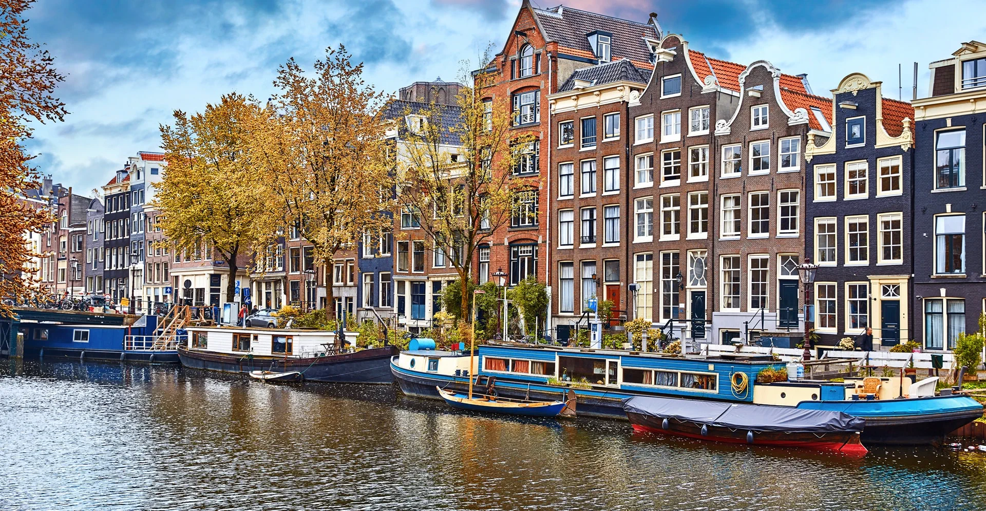 A scenic canal lined with buildings, featuring several boats gently floating on the water's surface.